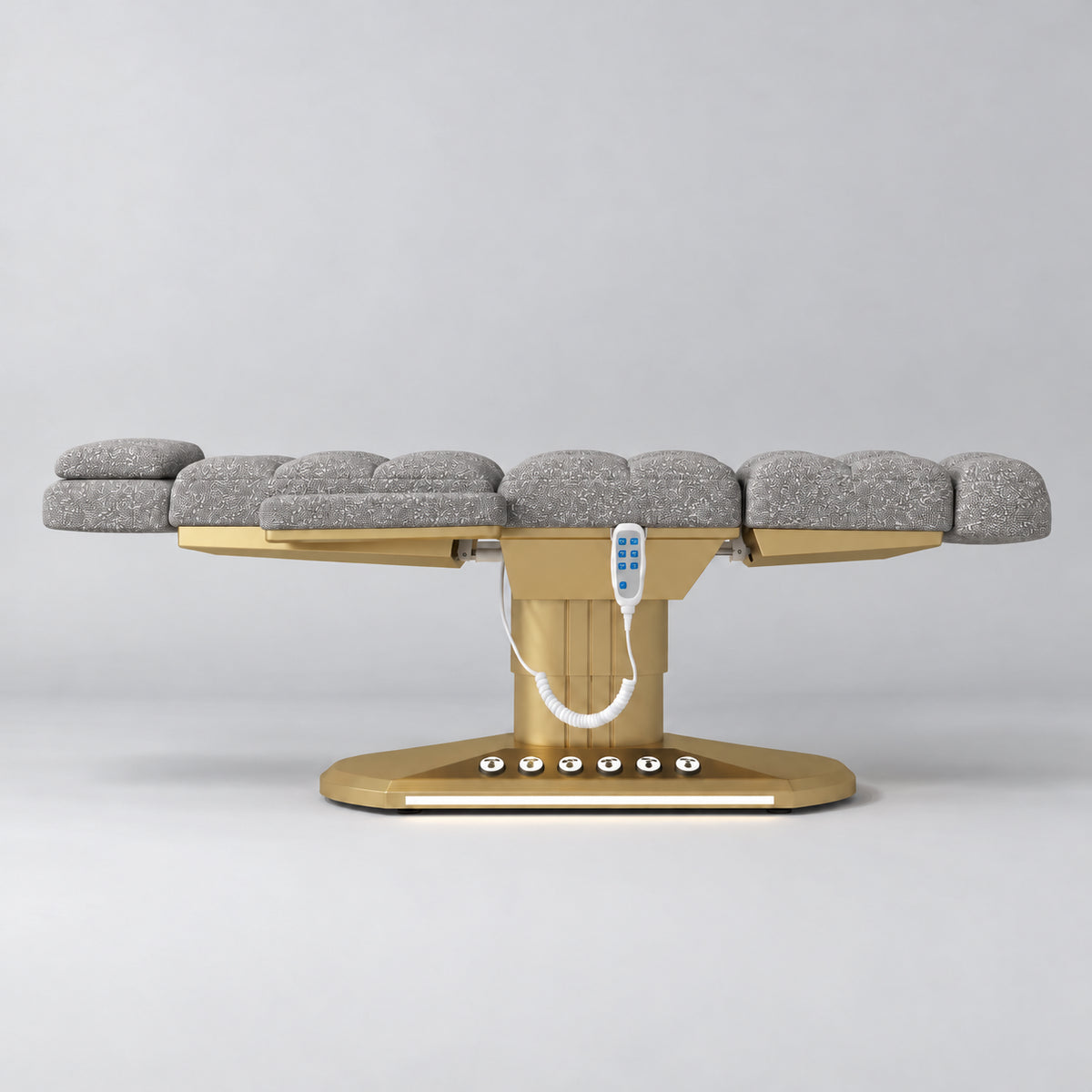 Manufakturo Orielle A Grey teddy electric beauty bed in a flat position viewed from the side, with gold oval base and hand-held controller.