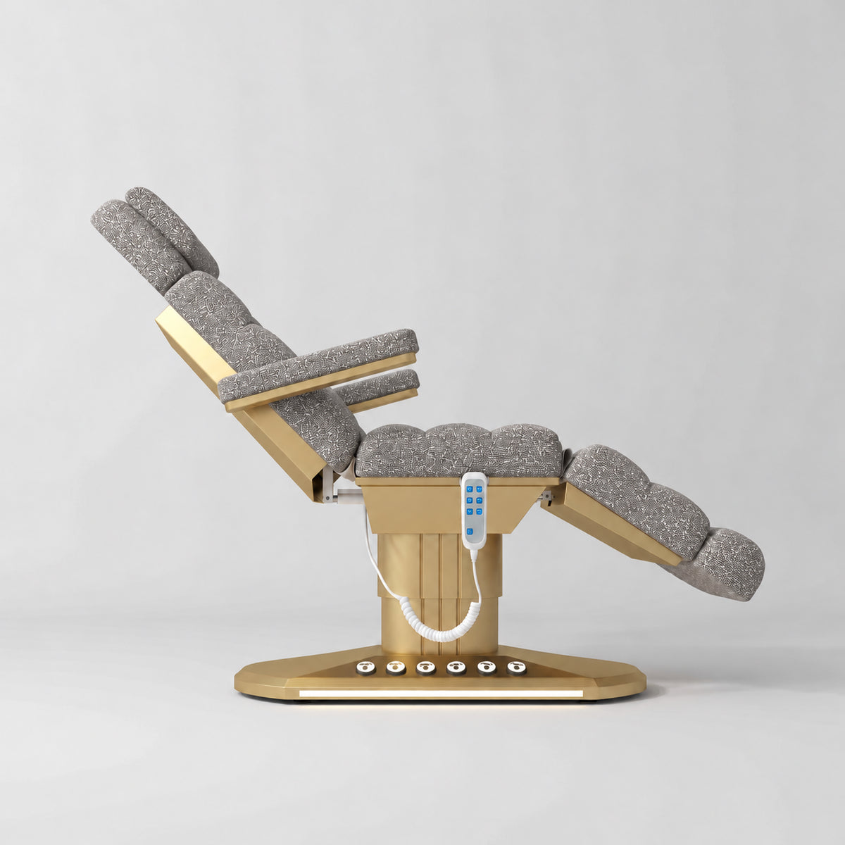 Manufakturo Orielle A Grey teddy electric beauty bed shown from the side in a treatment position, with gold oval base and hand-held controller.
