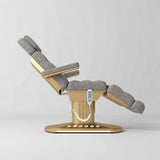 Manufakturo Orielle A Grey teddy electric beauty bed shown from the side in a treatment position, with gold oval base and hand-held controller.