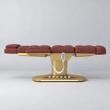 Manufakturo Orielle A Maroon teddy electric beauty bed in a flat position viewed from the side, with gold oval base and hand-held controller.