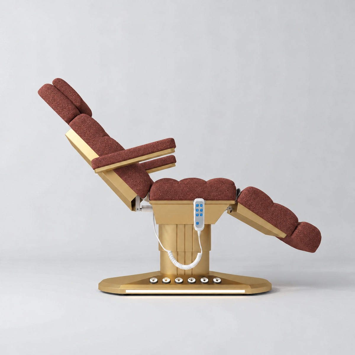 Manufakturo Orielle A Maroon teddy electric beauty bed shown from the side in a treatment position, with gold oval base and hand-held controller.