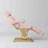 Manufakturo Orielle B Bare Blush electric beauty bed shown from the side in a treatment position, with gold base and hand-held controller.