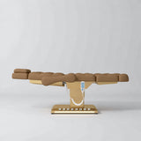 Manufakturo Orielle B Caramel electric beauty bed in a flat position viewed from the side, with gold base and hand-held controller.