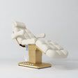 Manufakturo Orielle B Creamy electric beauty bed with gold base and current hand-held controller.