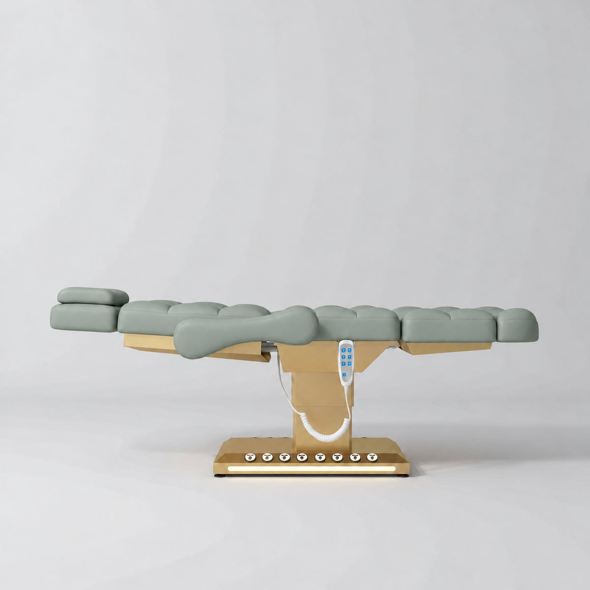 Manufakturo Orielle B Olive electric beauty bed in a flat position viewed from the side, with gold base and hand-held controller.