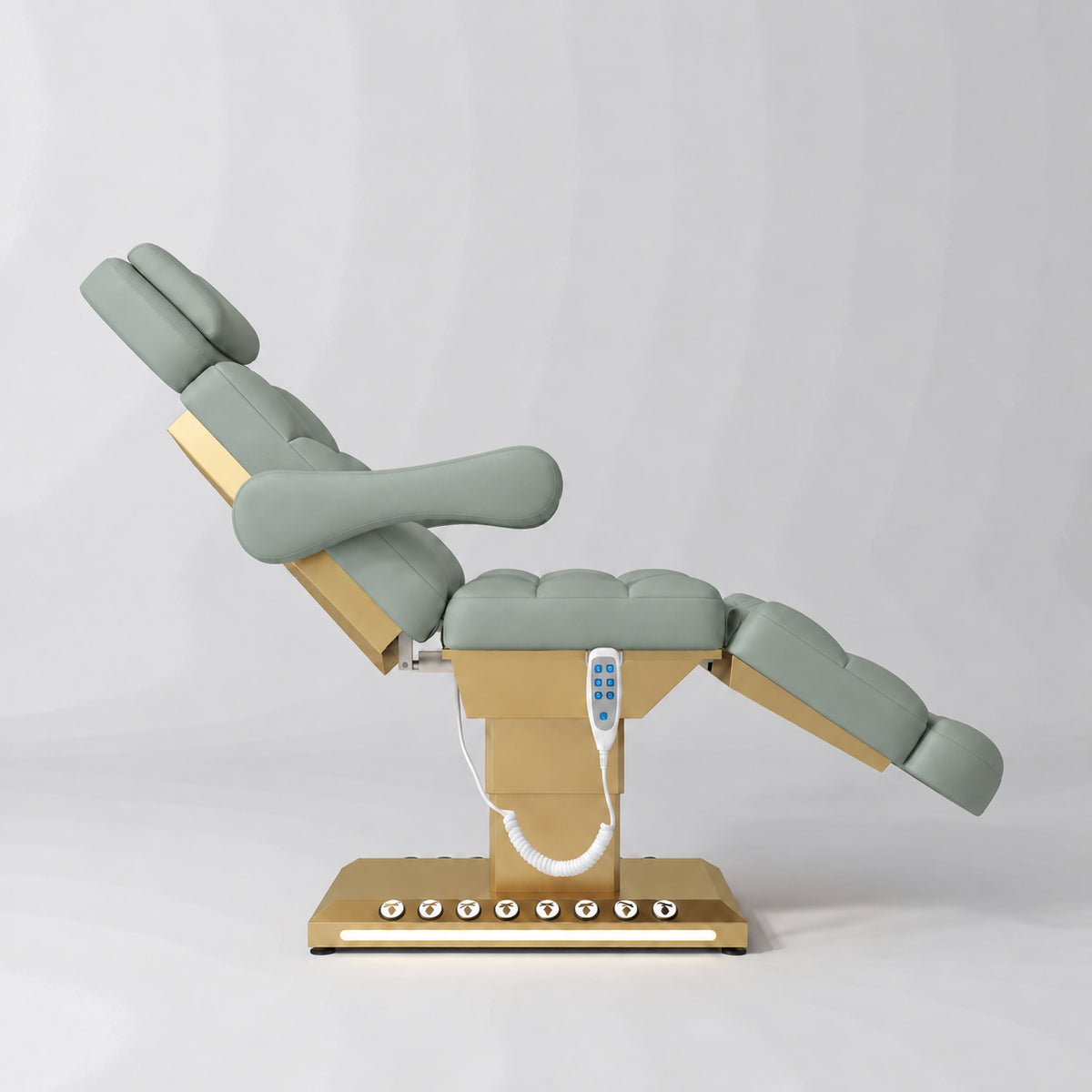 Manufakturo Orielle B Olive electric beauty bed shown from the side in a treatment position, with gold base and hand-held controller.
