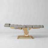 Manufakturo Orielle B Pearl Greige electric beauty bed in a flat position viewed from the side, with gold base and hand-held controller.