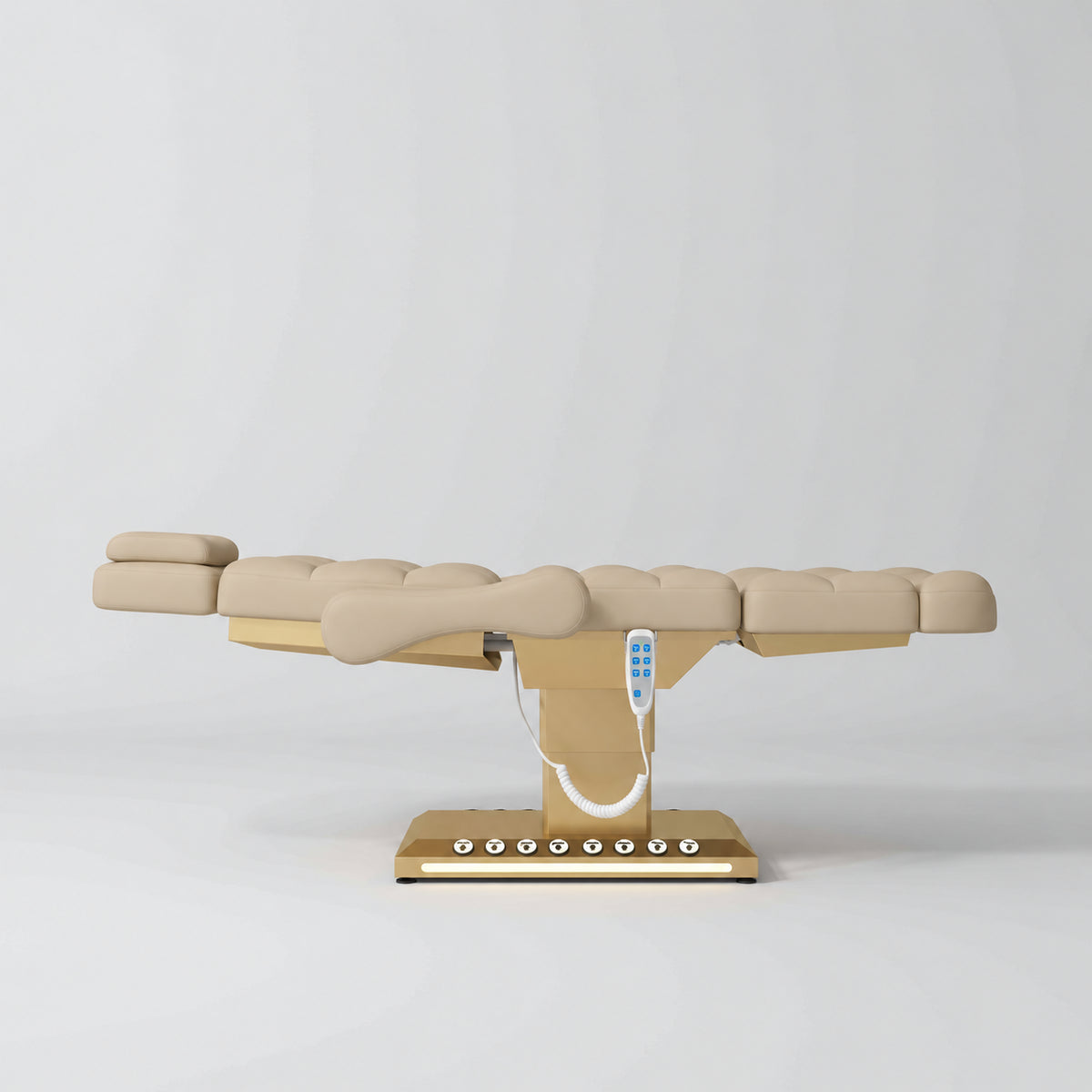 Manufakturo Orielle B Warm Beige electric beauty bed in a flat position viewed from the side, with gold base and hand-held controller.