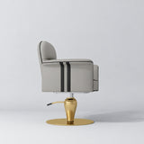 Side view of the Manufakturo Palais styling chair in Pearl Greige with black piping and a gold pedestal base, on a grey studio background.