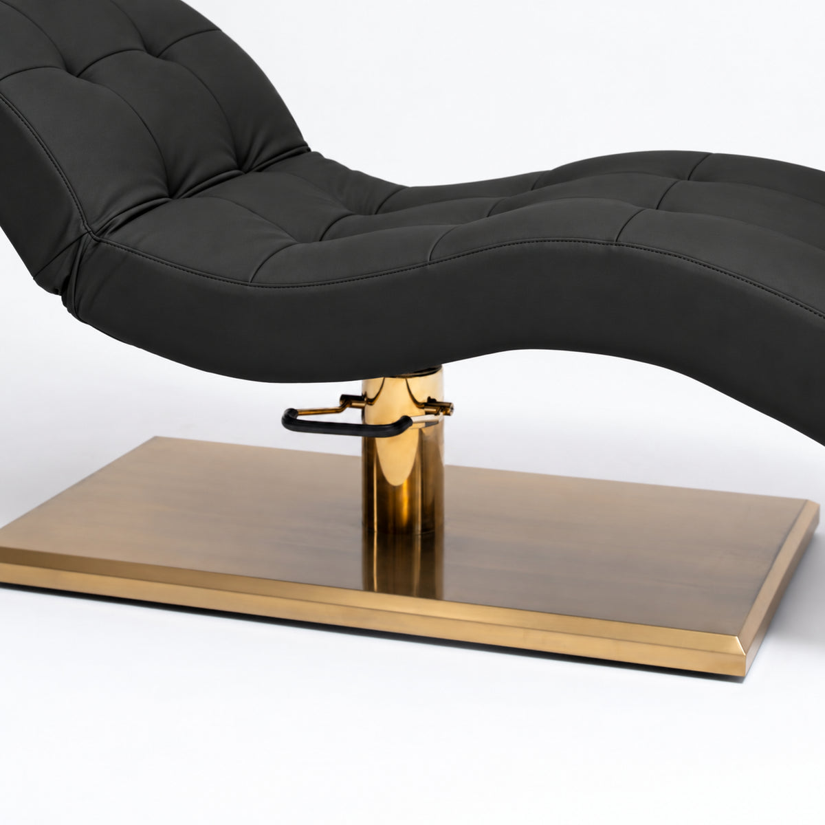 Manufakturo Prestige Black upholstered bed close-up with gold hydraulic pump, black foot pedal and rectangular gold base.