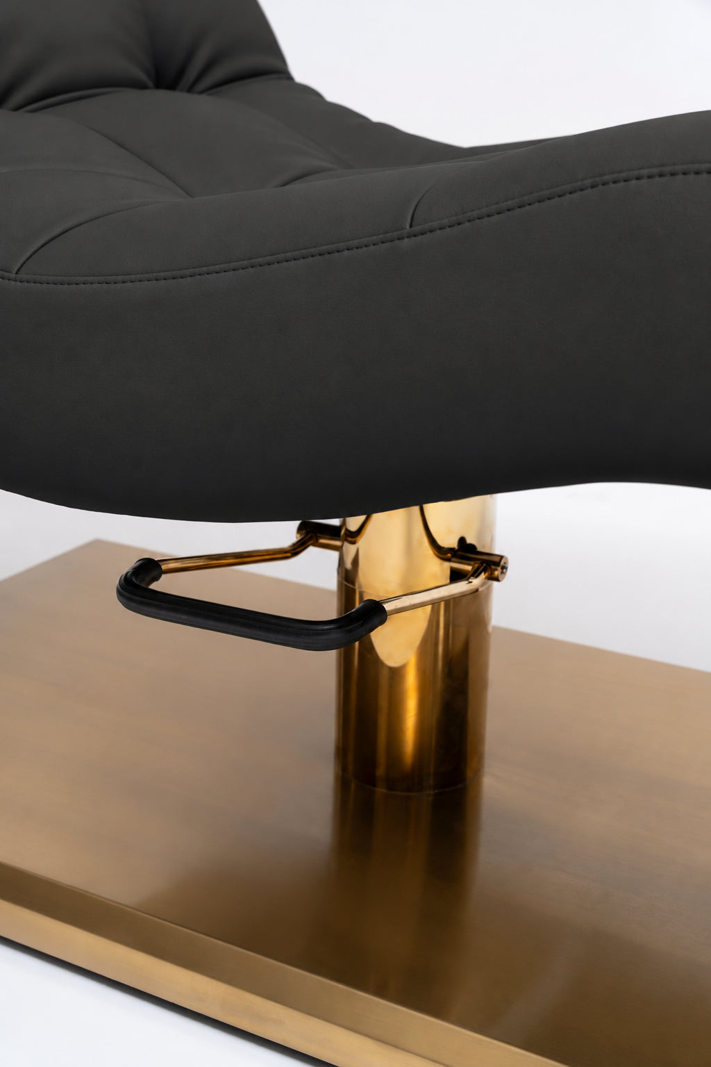 Manufakturo Prestige Black close-up of upholstered stitching, gold hydraulic column and black foot pedal.