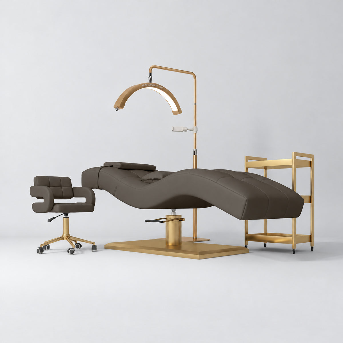 Manufakturo Prestige Cocoa Mocha studio set with hydraulic lash bed, Serenity chair, V3 Pro Gold lamp and empty gold trolley.