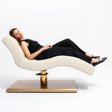 Manufakturo Prestige Creamy hydraulic beauty bed with a reclining client, showing contoured upholstery and gold base.