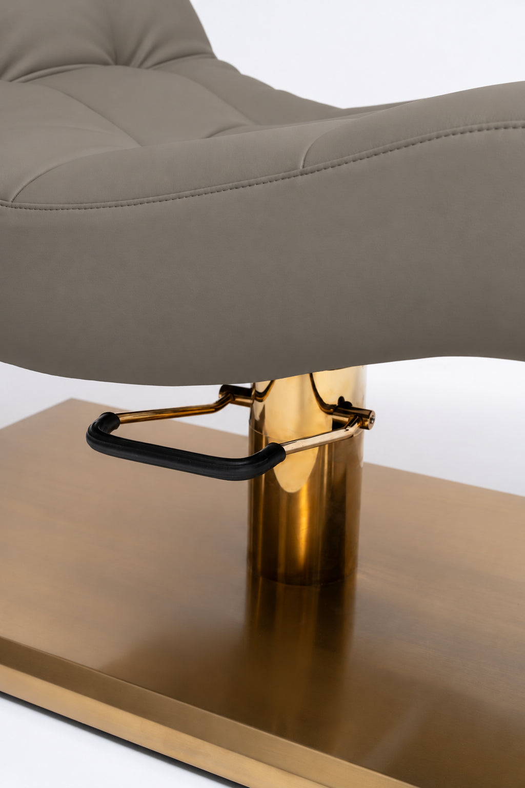 Manufakturo Prestige Deep Ash close-up of upholstered stitching, gold hydraulic column and black foot pedal.