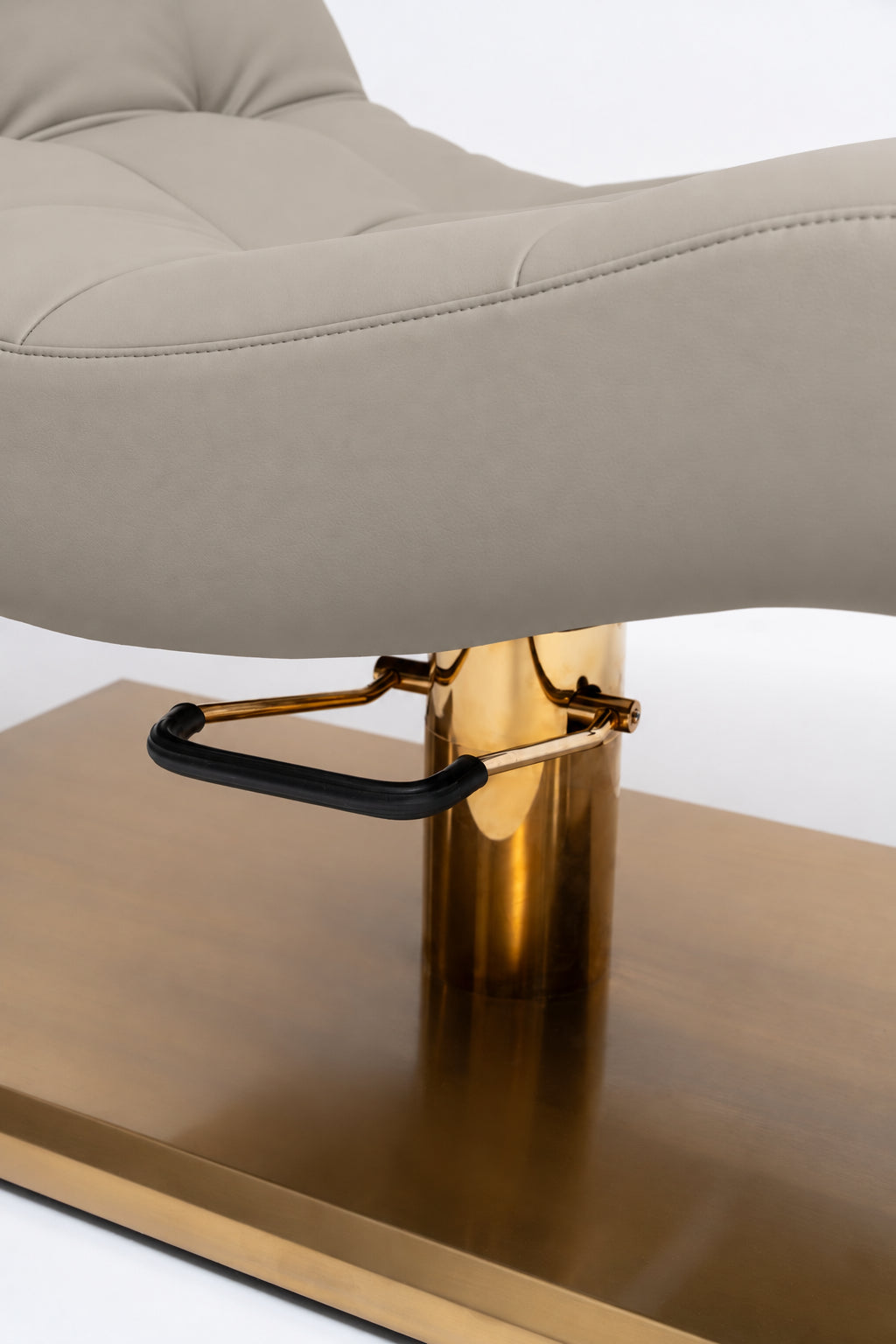 Manufakturo Prestige Stone Taupe close-up of upholstered stitching, gold hydraulic column and black foot pedal.
