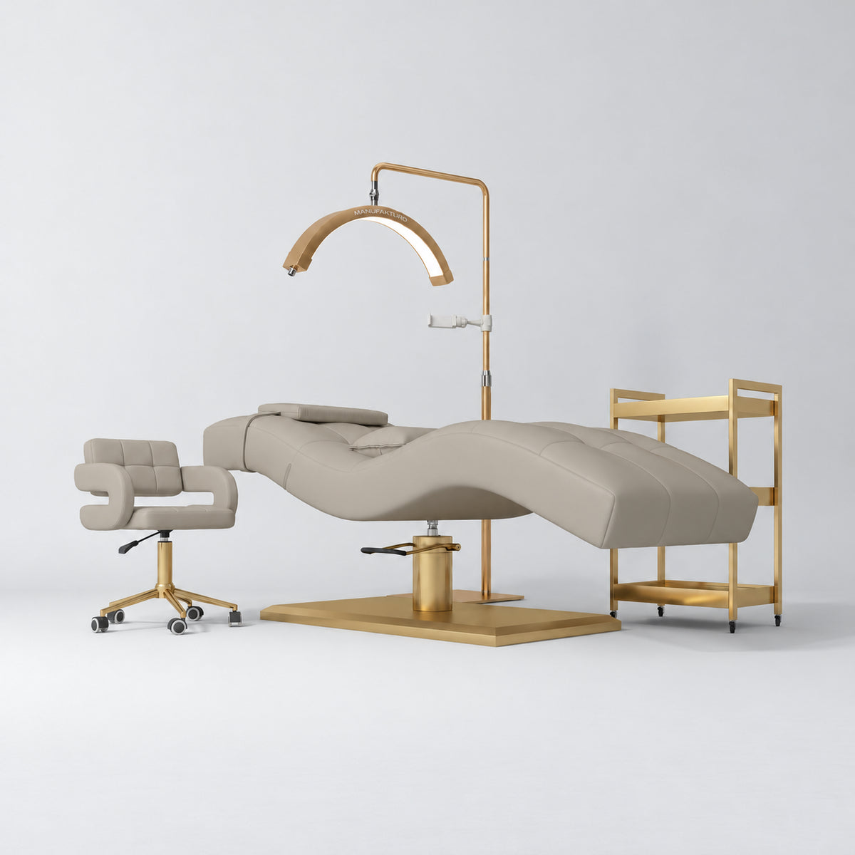 Manufakturo Prestige Stone Taupe studio set with hydraulic lash bed, Serenity chair, V3 Pro Gold lamp and empty gold trolley.