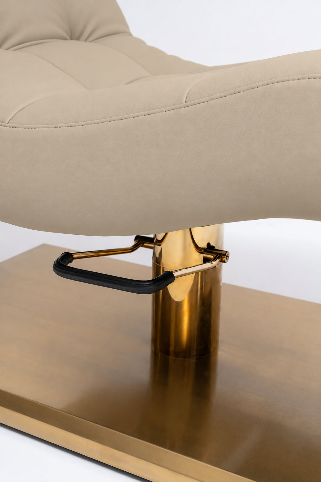 Manufakturo Prestige Warm Beige close-up of upholstered stitching, gold hydraulic column and black foot pedal.