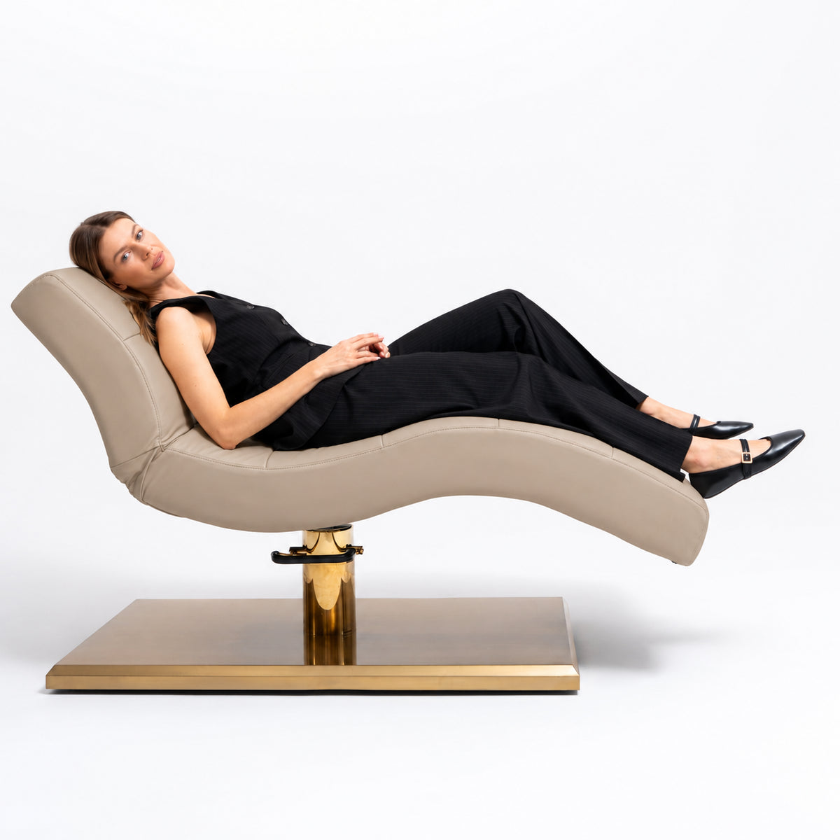 Manufakturo Prestige Warm Beige hydraulic beauty bed with a reclining client, showing the contoured support and gold base.