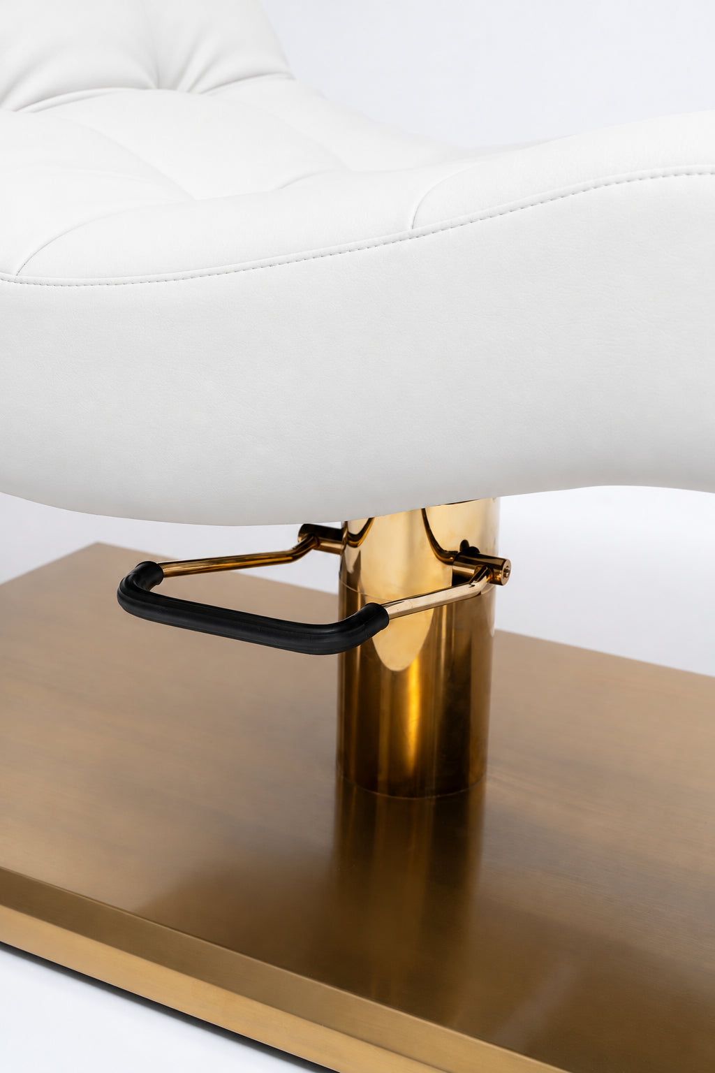 Manufakturo Prestige White close-up of upholstered stitching, gold hydraulic column and black foot pedal.