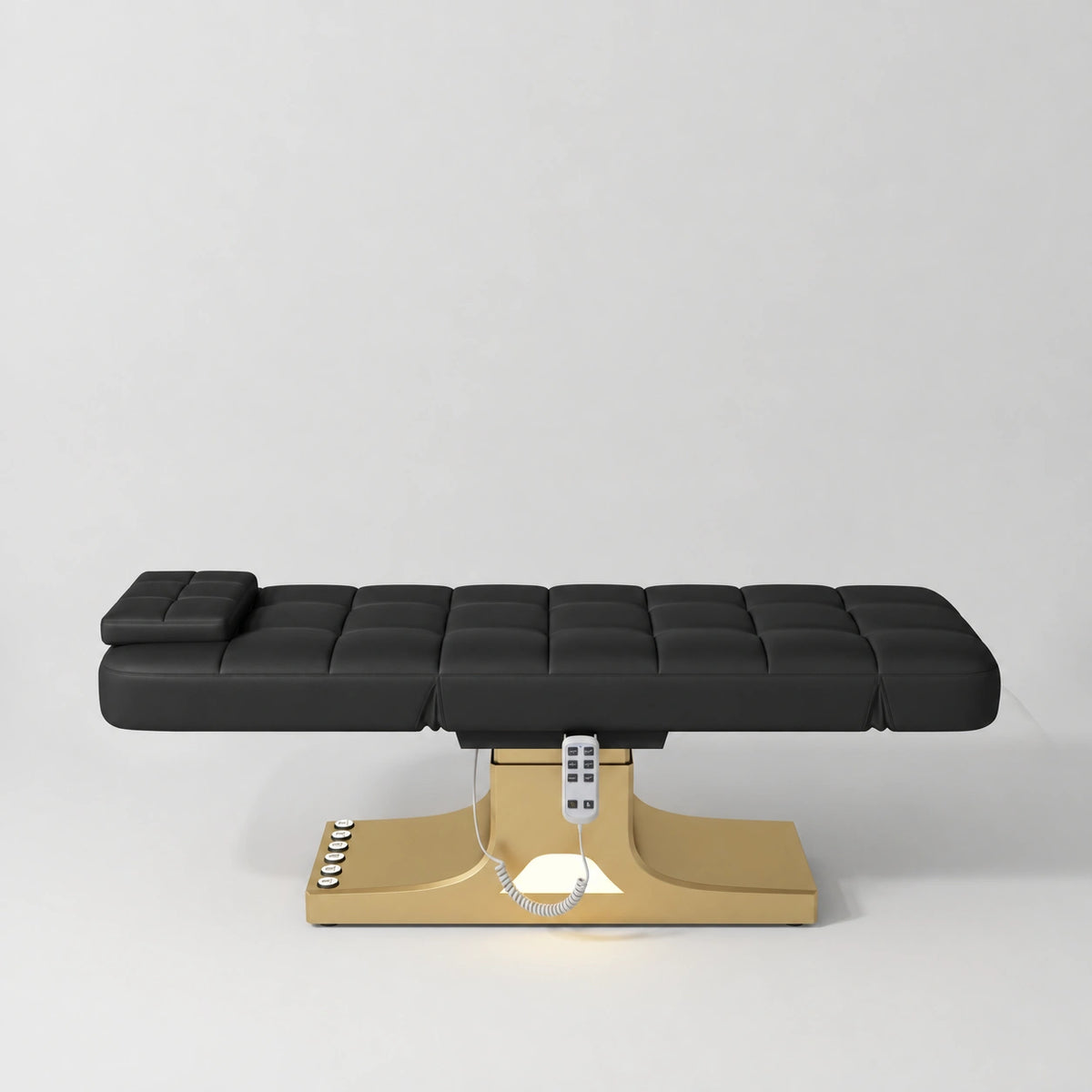 Manufakturo Saphir A Black electric beauty bed with gold base, flat lying position shown from the side, without armrests.