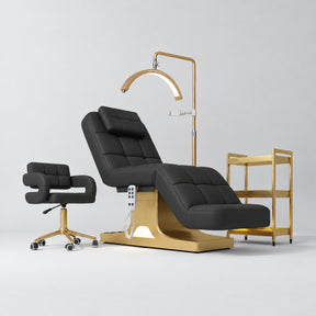 Manufakturo Saphir A Black four-piece beauty studio set with electric bed, Serenity salon chair, V3 Pro Gold lamp and empty three-tier gold trolley.