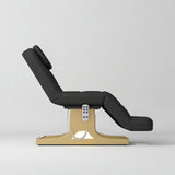 Manufakturo Saphir A Black electric beauty bed with gold base, raised treatment position shown from the side, without armrests.