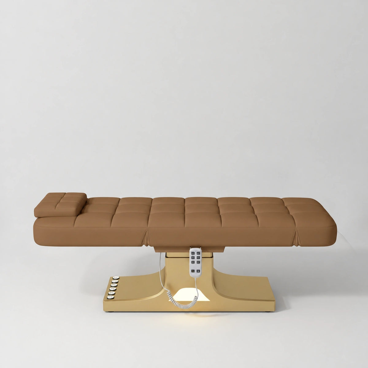 Manufakturo Saphir A Caramel electric beauty bed with gold base, flat lying position shown from the side, without armrests.