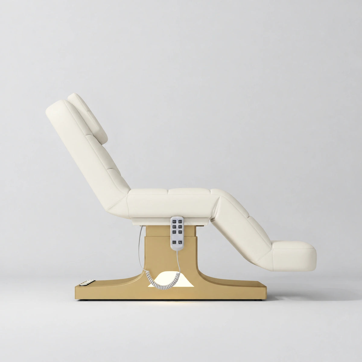 Manufakturo Saphir A Creamy electric beauty bed with gold base, raised treatment position shown from the side, without armrests.