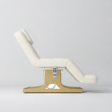 Manufakturo Saphir A Creamy electric beauty bed with gold base, raised treatment position shown from the side, without armrests.