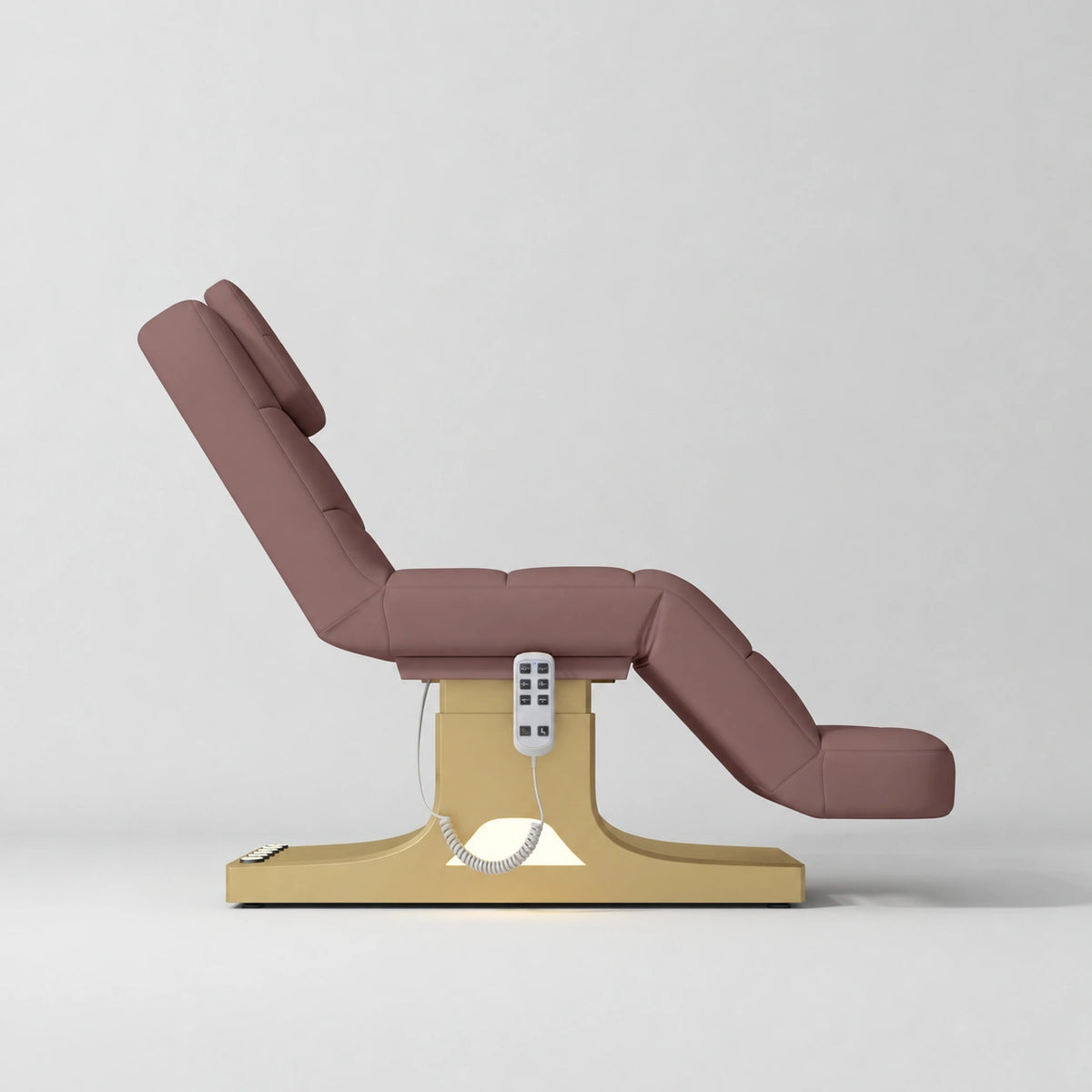 Manufakturo Saphir A Dusty Rose electric beauty bed with gold base, raised treatment position shown from the side, without armrests.