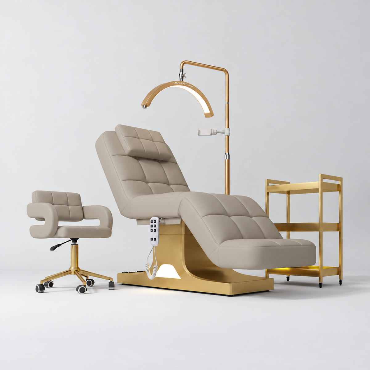 Manufakturo Saphir A Stone Taupe four-piece beauty studio set with electric bed, Serenity salon chair, V3 Pro Gold lamp and empty three-tier gold trolley.