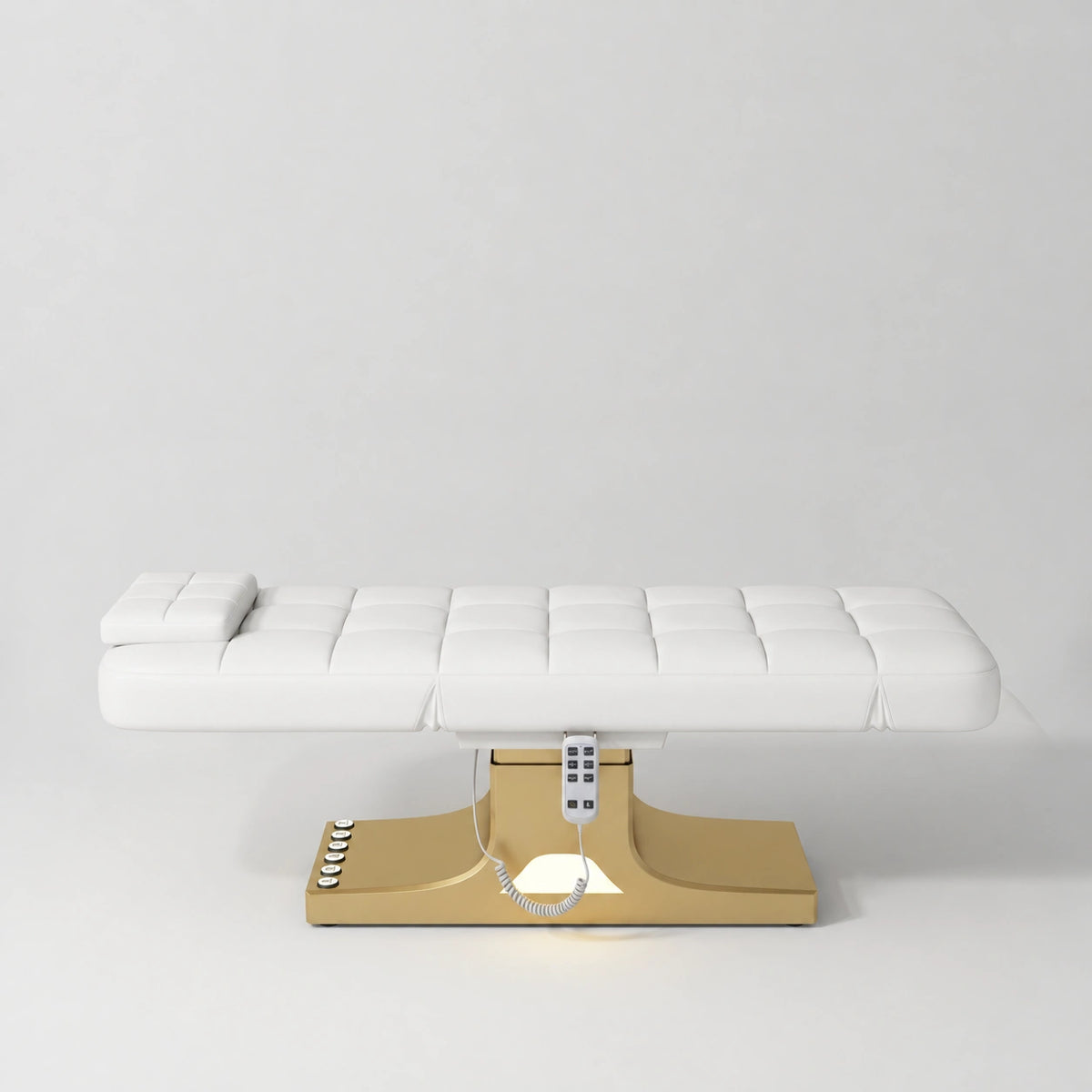 Manufakturo Saphir A White electric beauty bed with gold base, flat lying position shown from the side, without armrests.