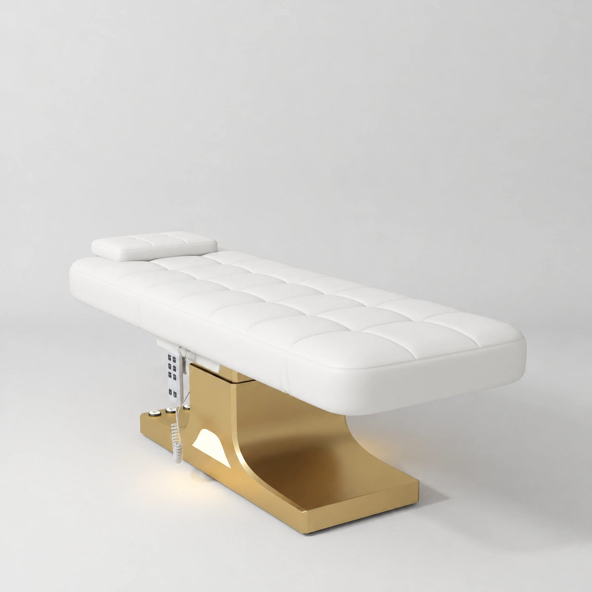 Manufakturo Saphir A White electric beauty bed with gold base, flat lying position shown in a three-quarter view, without armrests.