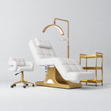 Manufakturo Saphir A White four-piece beauty studio set with electric bed, Serenity salon chair, V3 Pro Gold lamp and empty three-tier gold trolley.
