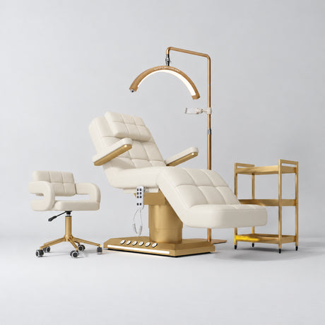 Manufakturo Saphir B Creamy four-piece beauty studio set with armrest electric bed, Serenity salon chair, V3 Pro Gold lamp and empty three-tier gold trolley.
