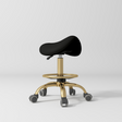 Manufakturo Selle Ergonomic Beauty Saddle Stool Black - Gold Base - displayed in a professional treatment-room setting