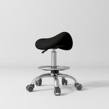 Manufakturo Selle Ergonomic Beauty Saddle Stool Black - Silver Base - displayed in a professional treatment-room setting