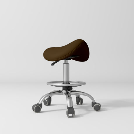 Manufakturo Selle Ergonomic Beauty Saddle Stool Cocoa Mocha - Silver Base - displayed in a professional treatment-room setting