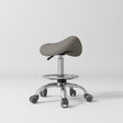Manufakturo Selle Ergonomic Beauty Saddle Stool Deep Ash - Silver Base - displayed in a professional treatment-room setting