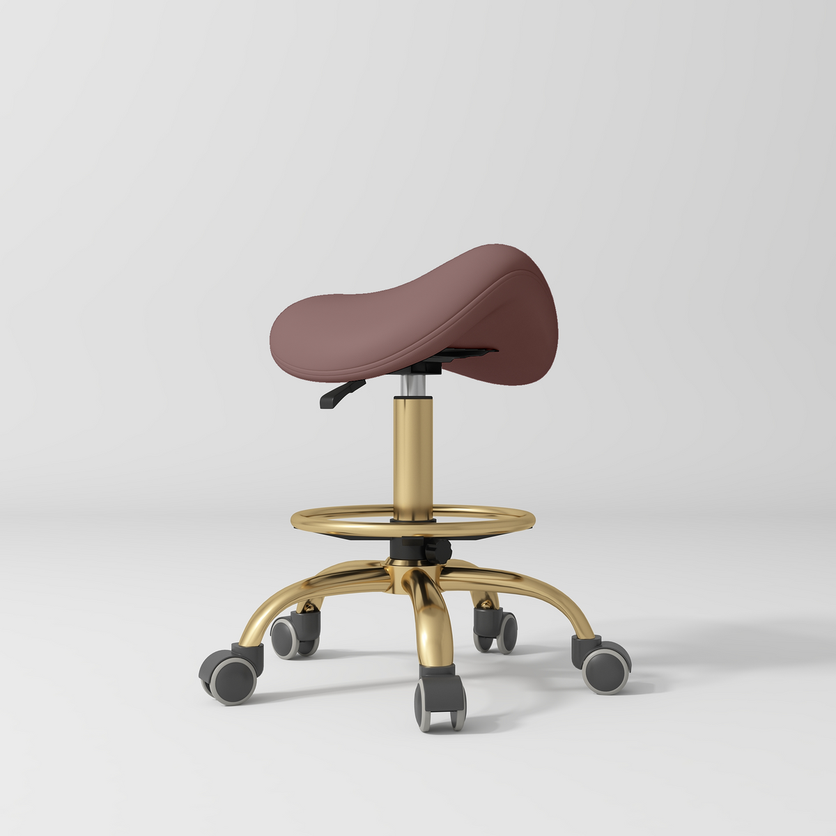 Manufakturo Selle Ergonomic Beauty Saddle Stool Dusty Rose - Gold Base - displayed in a professional treatment-room setting