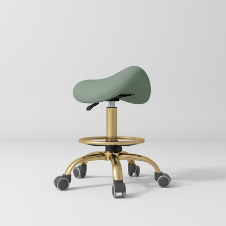 Manufakturo Selle Ergonomic Beauty Saddle Stool Olive - Gold Base - displayed in a professional treatment-room setting