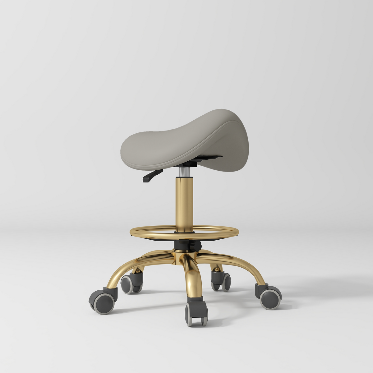 Manufakturo Selle Ergonomic Beauty Saddle Stool Pearl Greige - Gold Base - displayed in a professional treatment-room setting