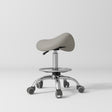 Manufakturo Selle Ergonomic Beauty Saddle Stool Pearl Greige - Silver Base - displayed in a professional treatment-room setting
