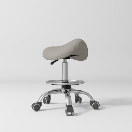 Manufakturo Selle Ergonomic Beauty Saddle Stool Pearl Greige - Silver Base - displayed in a professional treatment-room setting