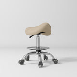 Manufakturo Selle Ergonomic Beauty Saddle Stool Warm Beige - Silver Base - displayed in a professional treatment-room setting