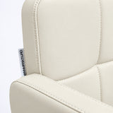 Close-up of Manufakturo Serenity Creamy salon chair upholstery, showing the stitched padded backrest, armrest piping and woven Manufakturo label.