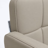 Close-up of Manufakturo Serenity Stone Taupe salon chair upholstery, showing the stitched padded backrest, armrest piping and woven Manufakturo label.