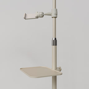 Close-up of the beige Manufakturo accessory tray clamped to a treatment lamp stand