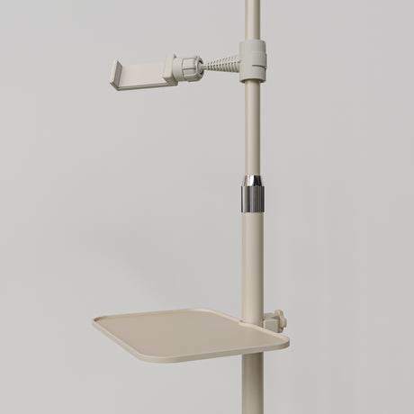 Close-up of the beige Manufakturo accessory tray clamped to a treatment lamp stand