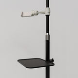 Close-up of the black Manufakturo accessory tray clamped to a treatment lamp stand